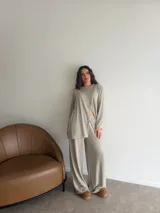 Conjunto de dos piezas color gris melange, confeccionado en tela de lanilla, compuesto por un buzo de manga larga con diseño cruzado al frente y un pantalón largo de corte holgado y tiro alto.