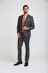 Ambo de hombre compuesto por saco de dos botones y pantalón de vestir a juego, en color gris oscuro. Incluye camisa rosa y corbata estampada en tonos rosados.