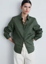 Camisa de corte recto color verde militar, con cuello camisero, cierre frontal de botones, manga larga abotonada y un bolsillo de parche en el pecho.