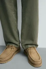 Zapato de cordones con parte superior de piel con acabado serraje, detalle de bordón en el empeine, horma redonda y suela a tono con piso track.