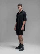 Camisa de corte oversize color negro, confeccionada en lino, con cuello tipo cubano, cierre frontal de botones y mangas cortas.