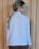 Camisa de manga larga con estampado de rayas verticales en tonos crudo y beige. Presenta cuello alto con volados, cierre frontal con botones dobles y puños con volados.