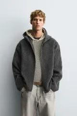 Sobrecamisa de corte relajado confeccionada en tejido con textura efecto pelo. Presenta cuello con capucha, manga larga, bolsillos laterales y cierre frontal con cremallera.