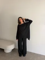 Conjunto compuesto por una blusa de manga larga con escote amplio y un pantalón largo de corte recto, ambos en color negro.