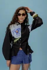 Camisa verde con lunares violetas, cuello clásico, mangas abullonadas y lazos laterales para ajustar.