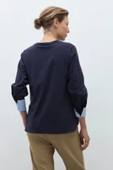 Remera de manga larga color azul marino, con cuello redondo y puños en contraste con diseño de rayas verticales celestes y blancas.
