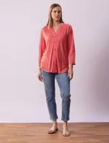 Blusa Ninety color beige con textura, cuello base con escote en V y abertura central con botones. Tiene un bolsillo en el pecho y mangas 3/4 regulables con presilla y botón.