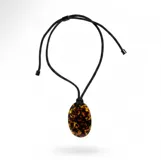 Collar con dije ovalado de resina con estampado tipo carey, montado sobre un cordón negro ajustable con terminaciones metálicas.