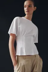 Camiseta de algodón con cuello redondo y manga corta. Presenta un diseño entallado con pinzas en la cintura y bajo recto.