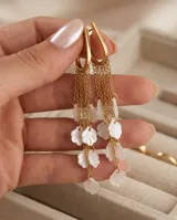 Caravanas colgantes de acero con baño de oro, compuestas por una estructura superior tipo gancho y múltiples cadenas finas que terminan en pequeños pétalos de resina blanca.