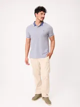 Remera polo de piqué de algodón melange color celeste, con cuello y puños en contraste blanco y azul, cierre frontal con botones y bordado pequeño en el pecho.