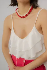 Musculosa blanca de tirantes finos regulables, con escote en V y diseño con volados escalonados en el frente.
