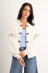 Campera oversize color crudo de algodón con spandex, corte de largo intermedio, mangas largas con detalles de costuras en zigzag bordadas y un gran diseño bordado a mano de una flor en la espalda.