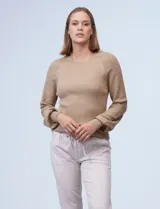Buzo color beige de tejido combinado con mangas largas caladas y cuello redondo.