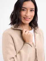 Campera de tejido de punto en color beige, con cierre frontal completo, cuello alto y mangas largas con puños acanalados.