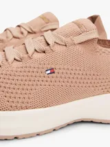 Zapatillas de estilo running con exterior de punto elástico color beige, diseño de corte bajo con ajuste estilo calcetín y cierre de cordones. Presenta el logo de Tommy Hilfiger bordado en el lateral y suela de goma blanca.