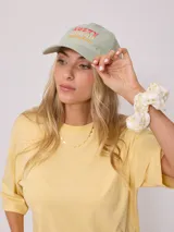 Gorro de visera color lila, estilo dad hat, de lona lavada con bordado frontal en blanco que dice "RUSTY AUSTRALIA MERMAID BEACH".
