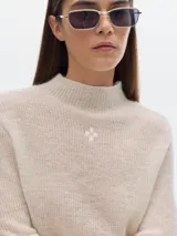 Polera azul de tejido suave con cuello alto y manga larga. Tiene un pequeño bordado en el frente y otro en la manga.