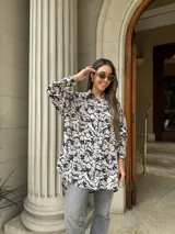 Camisa blanca con estampado floral negro, de corte amplio y mangas largas.