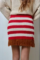 Minifalda tejida a mano en hilado de algodón, con diseño a rayas horizontales en color amarillo y blanco. Presenta flecos marrones en el ruedo.
