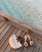 Bolso de mano con forma de media luna cubierto de perlas sintéticas. Tiene asas circulares de madera y detalles de cuentas en la unión con el cuerpo del bolso.