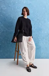 Sweater blanco de punto con diseño holgado, cuello redondo, mangas largas acampanadas y detalles de textura horizontal en el tejido.