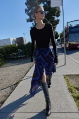 Falda midi de corte asimétrico con diseño cruzado en el delantero y aberturas. Presenta un estampado geométrico en tonos azul, negro y beige, con forro interior y cierre trasero con cremallera oculta.