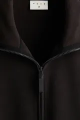 Buzo deportivo de polar negro, con cuello alto y cierre parcial frontal. Presenta mangas largas con puños ajustados y corte relajado.