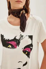Remera de algodón color crudo con estampa frontal gráfica de estilo pixelado que representa un rostro con detalles en fucsia y amarillo.