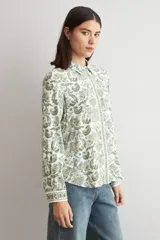 Camisa de manga larga con estampado paisley en tonos verdes sobre base blanca, con cuello camisero y cierre frontal de botones.
