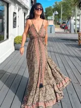 Vestido largo tipo solera, con escote en V profundo y tirantes finos. Presenta un estampado paisley en tonos rosados, lilas y blancos, con ajuste de lazo en la cintura y volados en el ruedo.