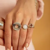 Anillo de plata 925 con diseño de doble banda que conecta un círculo plano grande con un dije circular pequeño grabado.