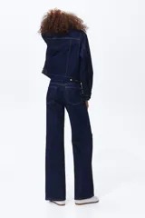 Jean de tiro alto confeccionado en denim de algodón lavado, con diseño de cinco bolsillos y piernas rectas de corte holgado. Cierre frontal con botón y cremallera.