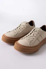 Championes urbanos de cuero en color crema con suela de goma gruesa en tono caramelo. Presentan detalles de costuras decorativas en el lateral y un refuerzo en el talón en color gris.