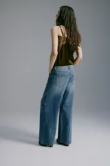 Jean wide leg de denim azul con lavado medio, tiro regular, diseño de cinco bolsillos y perneras amplias y rectas.