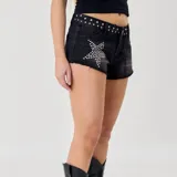 Short de denim negro con efecto deslavado, tiro medio y botamanga deshilachada. Presenta tachas metálicas plateadas decorativas en la pretina y un diseño de estrella formado por tachas en el bolsillo delantero.
