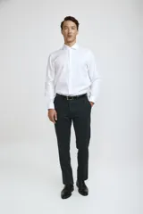 Camisa de vestir blanca de corte clásico, con cuello rígido, cierre frontal de botones y mangas largas con puños abotonados.