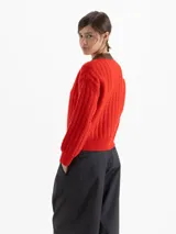 Sweater de punto con diseño de ochos y rayas verticales en color rojo. Presenta cuello redondo, puños y cintura en contraste de color marrón oscuro.