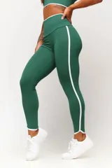 Calza deportiva de tiro alto color verde oscuro con una franja lateral blanca que recorre la pierna. El borde inferior de la calza tiene un corte asimétrico con ribete blanco.