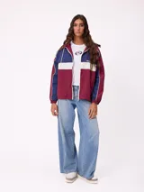 Campera rompevientos Rusty con diseño color block en tonos bordó, azul y blanco. Cuenta con cierre frontal, capucha con cordones ajustables, puños elásticos y logo bordado en el pecho.