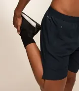 Bermuda deportiva gris con cintura elástica, cordón de ajuste, bolsillos con cremallera, recorte lateral con agujeritos y abertura en el bajo.