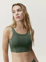 Top deportivo negro con sujetador interno de sujeción media-alta, tejido Shapplex_B con tecnología performance, vivos blancos en contraste en delantero y espalda, y logo en el pecho.