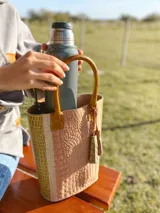 Bolso matero de cuero color nude con textura croco y laterales en color pistacho. Tiene manijas cortas de cuero color suela y un dije de cuero con flecos.