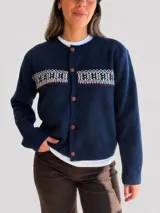 Cárdigan de punto azul marino con diseño jacquard en la parte superior del pecho. Presenta cuello redondo, cierre frontal con botones marrones y puños y ruedo acanalados.