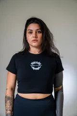Remera negra corta ajustada al cuerpo con estampado frontal de dientes y texto en blanco.