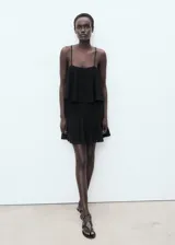 Vestido corto negro de punto fino, sin mangas, con tirantes finos, escote cuadrado y maxi volante superpuesto en el pecho con diseño evasé.