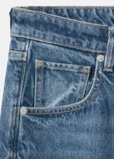 Jeans estilo wide leg de tiro medio con diseño de cinco bolsillos, trabillas para cinturón, cierre de botón y cremallera, y bajo vuelto.