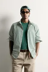 Camisa relaxed fit confeccionada en tejido de algodón, con diseño de rayas verticales en tonos azul y blanco, cuello con botones y manga larga.