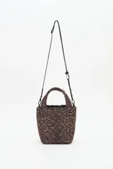 Bolso tipo tote mini acolchado con estampado de leopardo en tonos marrones y negros. Presenta asas cortas acolchadas y una correa larga ajustable con inscripción. Incluye un llavero colgante con letras negras.