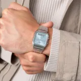 Reloj Casio de estilo vintage con diseño ana-digi, caja cuadrada de acero inoxidable y esfera color celeste. Cuenta con brazalete de eslabones metálicos, manecillas para hora analógica y pantalla digital inferior para funciones adicionales.